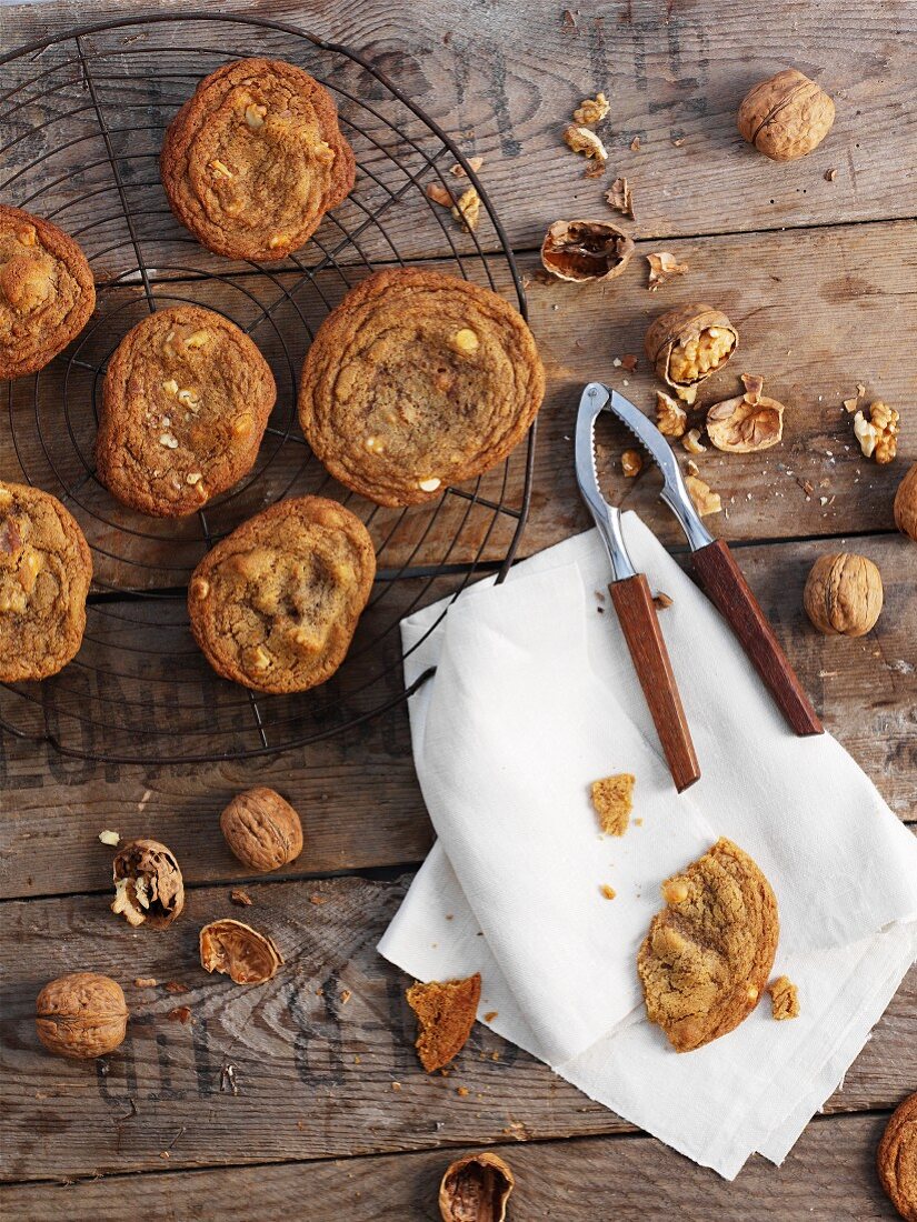 Walnut biscuits on a cooling rack, a nutcracker and walnuts