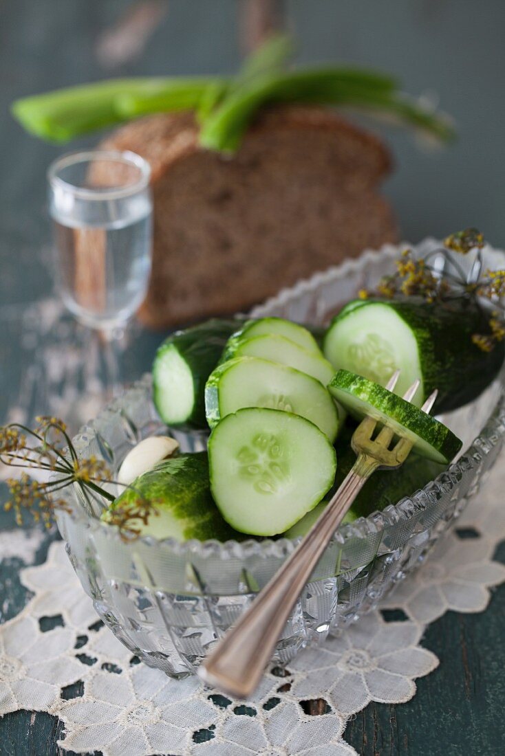 Salted cucumbers in glass bowl with bread and vodka
