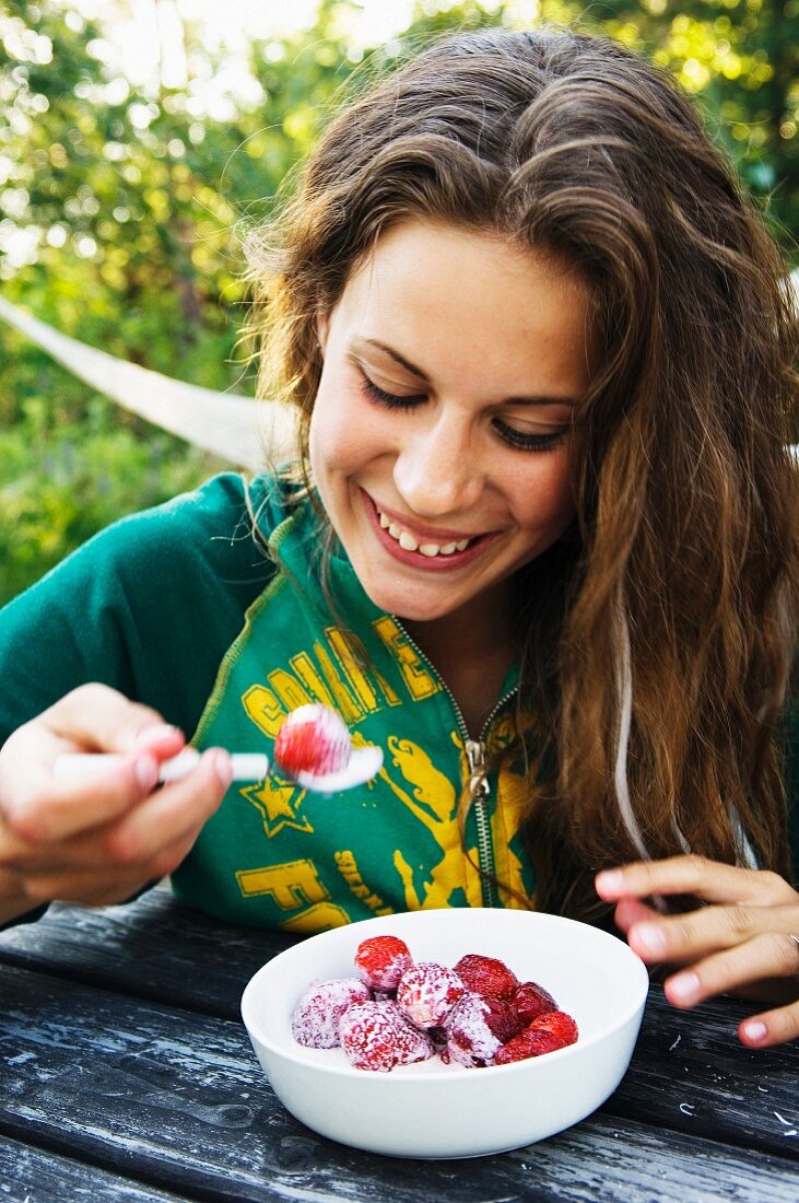 Mädchen isst Erdbeeren mit Milch
