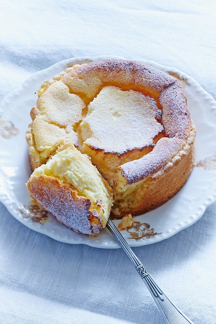 Baked cheesecake with icing sugar, one portion cut