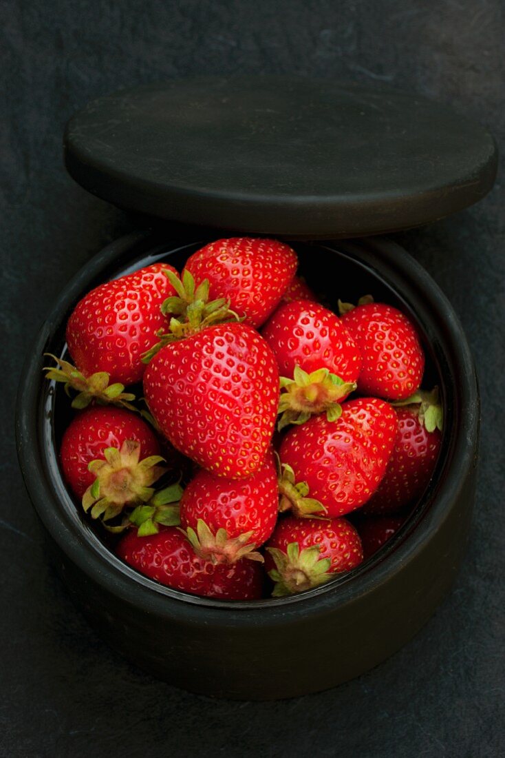 Fresh organic strawberries in a black ceramic dish