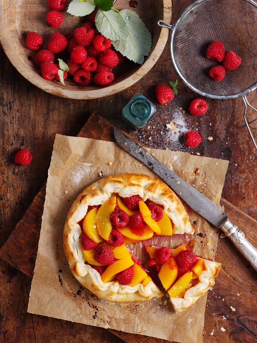 Peach and raspberry tart, one slice cut