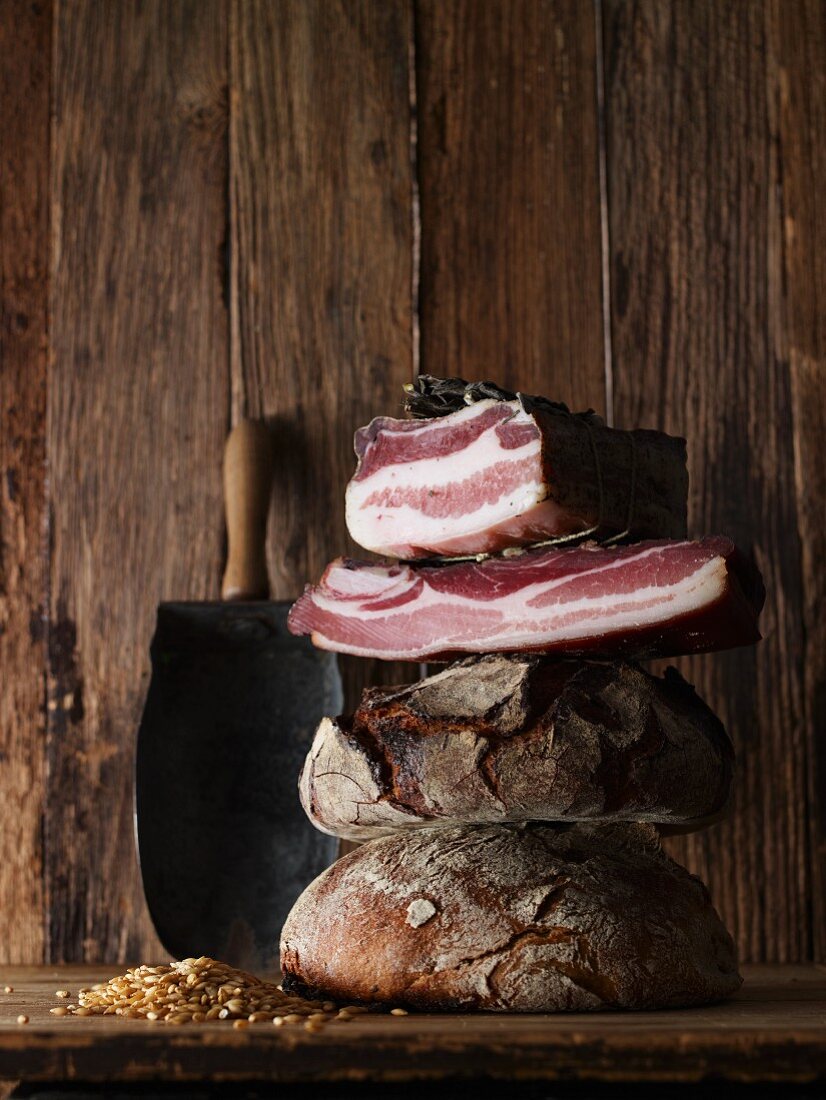 Rustic bread, cured ham and cereal grains on a wooden surface