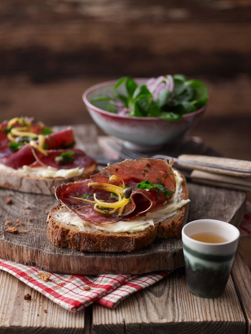 Bauernbrot mit Bündnerfleisch, Kapern, Zitronenschale und Feldsalat