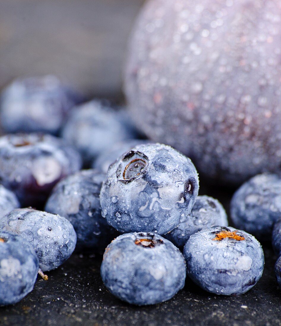 Heidelbeeren mit Wassertropfen vor einer Feige