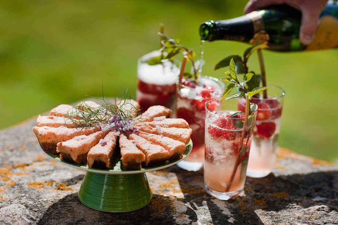 Sektcocktails und Lachsbrote auf Steintisch im Garten