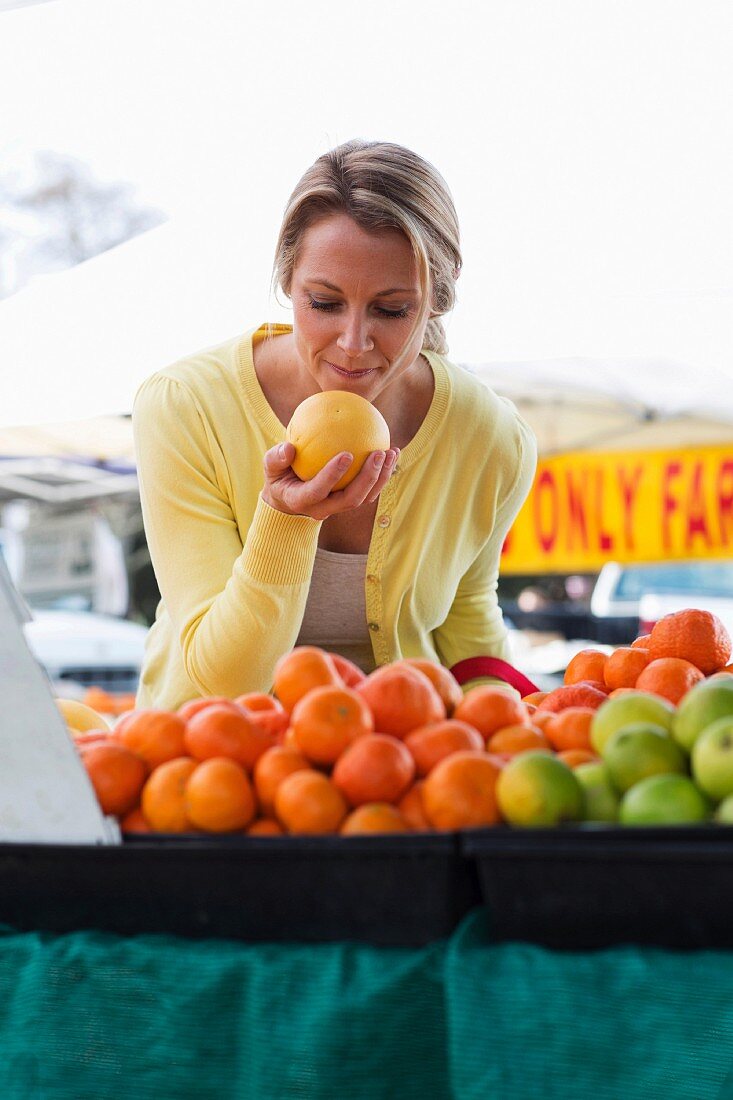A woman with grapefruit at a vegetable stall