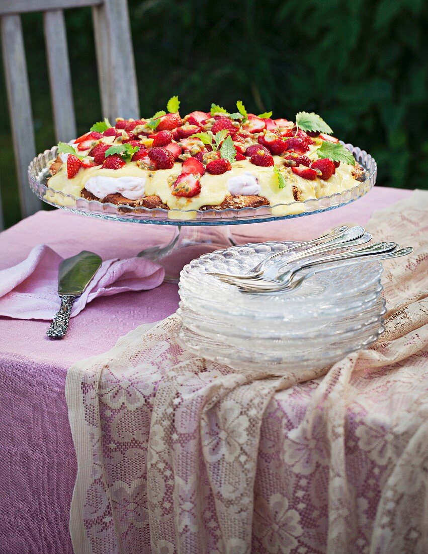 Erdbeerkuchen mit Vanillesauce auf Gartentisch