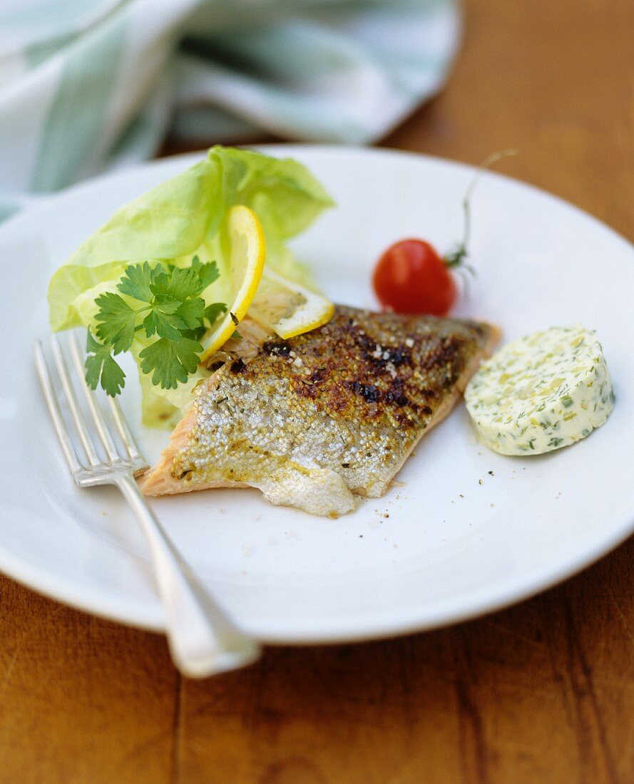 Pan-fried salmon fillet with herb butter and a salad garnish