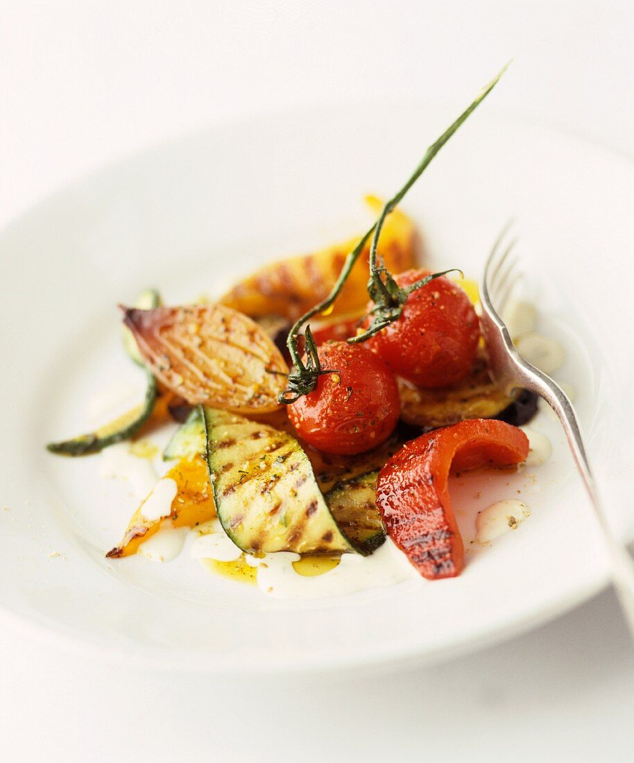 A plate of grilled vegetables, with courgette, onion, peppers and tomatoes