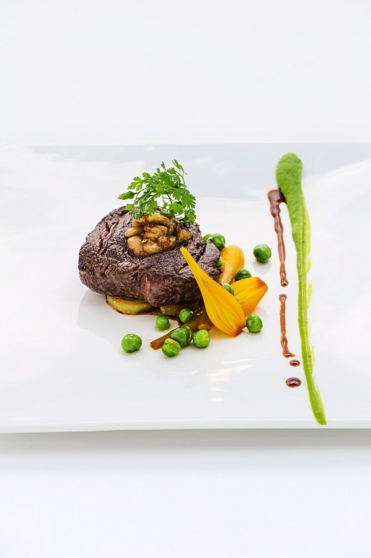 Roast beef fillet steak with a bone marrow and vegetable filling, saffron onions and peas