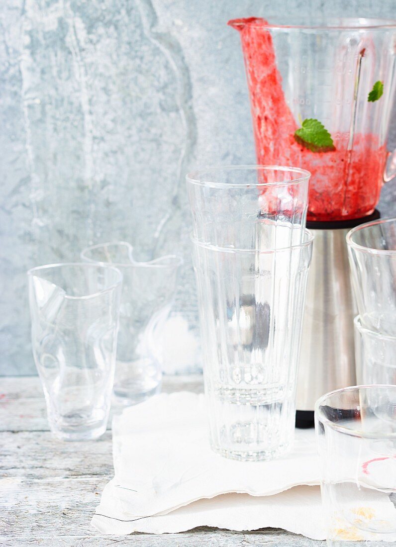 A blender with remains of juice, and empty glasses