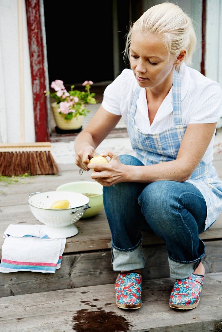 Young woman peeling potatoes