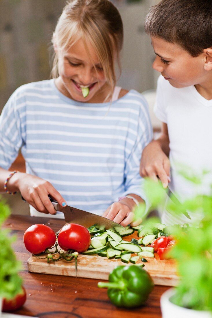 A girl and a boy cutting vegetables