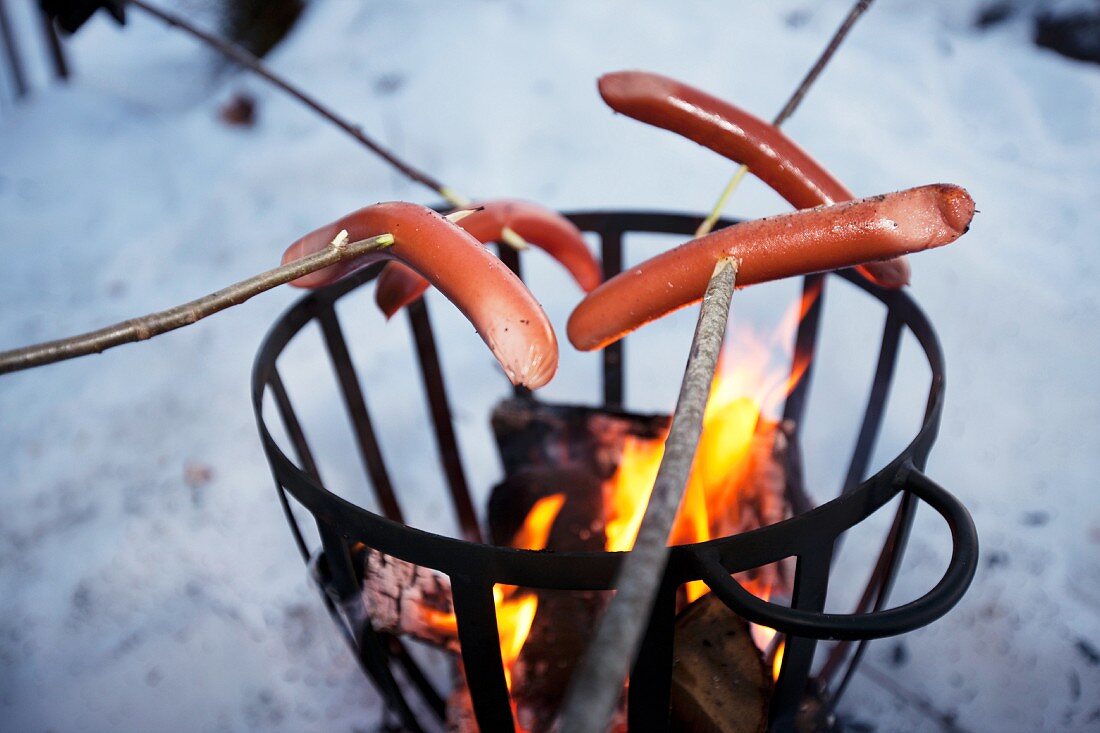 Sausages on sticks above fire