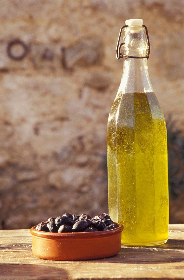 Stillleben mit Olivenöl und schwarzen Oliven