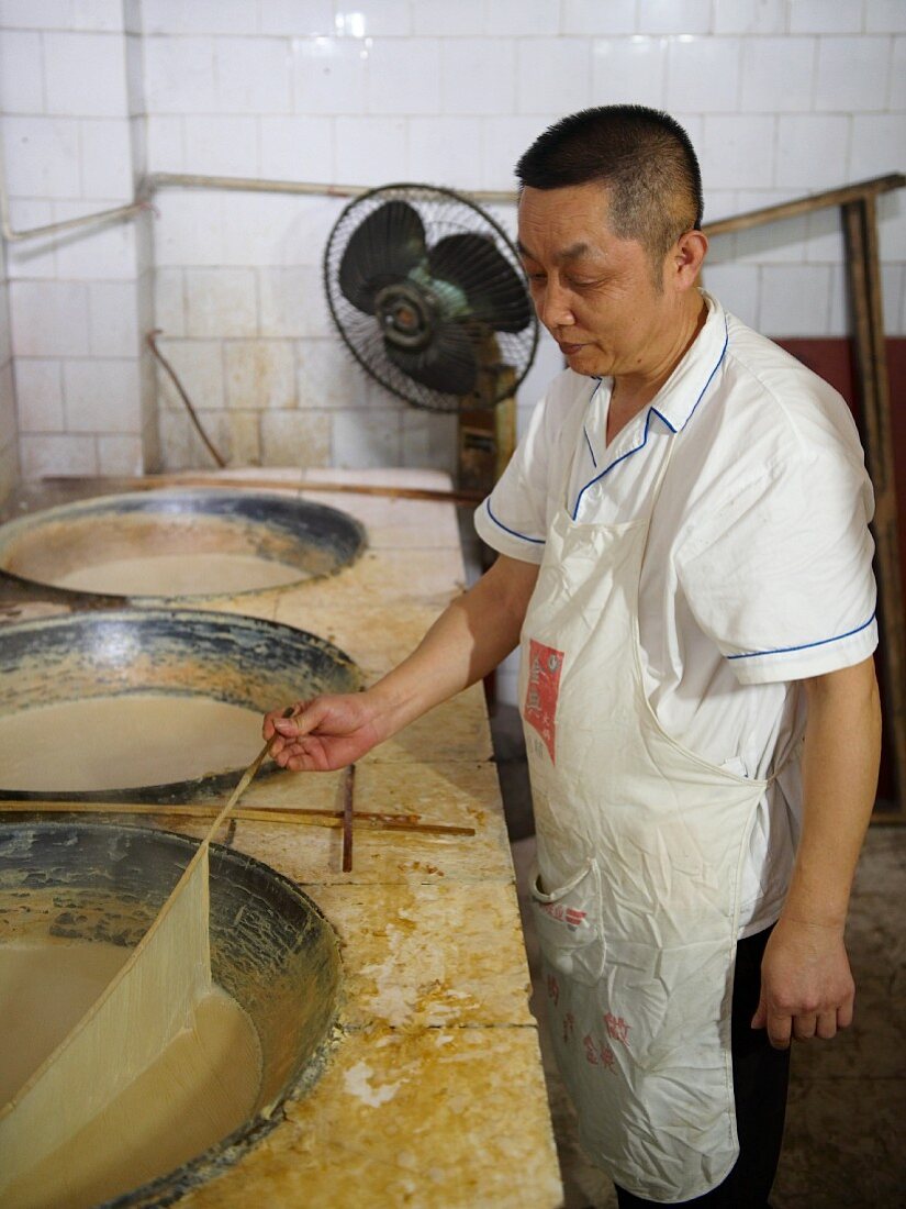 Chinesischer Koch beim Herstellen von Tofuhaut