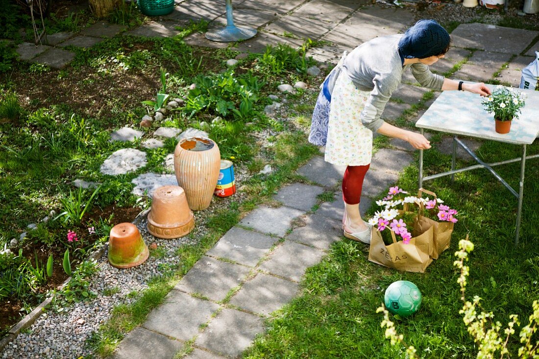 Frau mit Blumentopf in sonnigem Garten