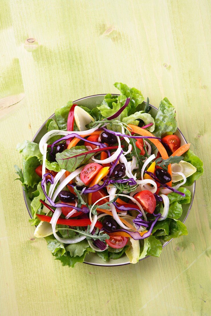 Mixed salad leaves with sliced vegetables, tomatoes and olives