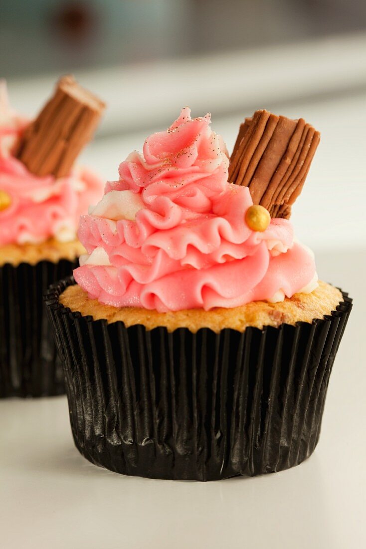 Vanillecupcake mit rosa Buttercreme und Schokoröllchen