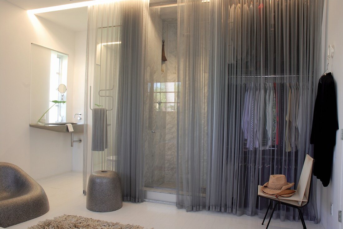 Modern dressing area and ensuite bathroom partitioned from bedroom by grey, translucent curtains