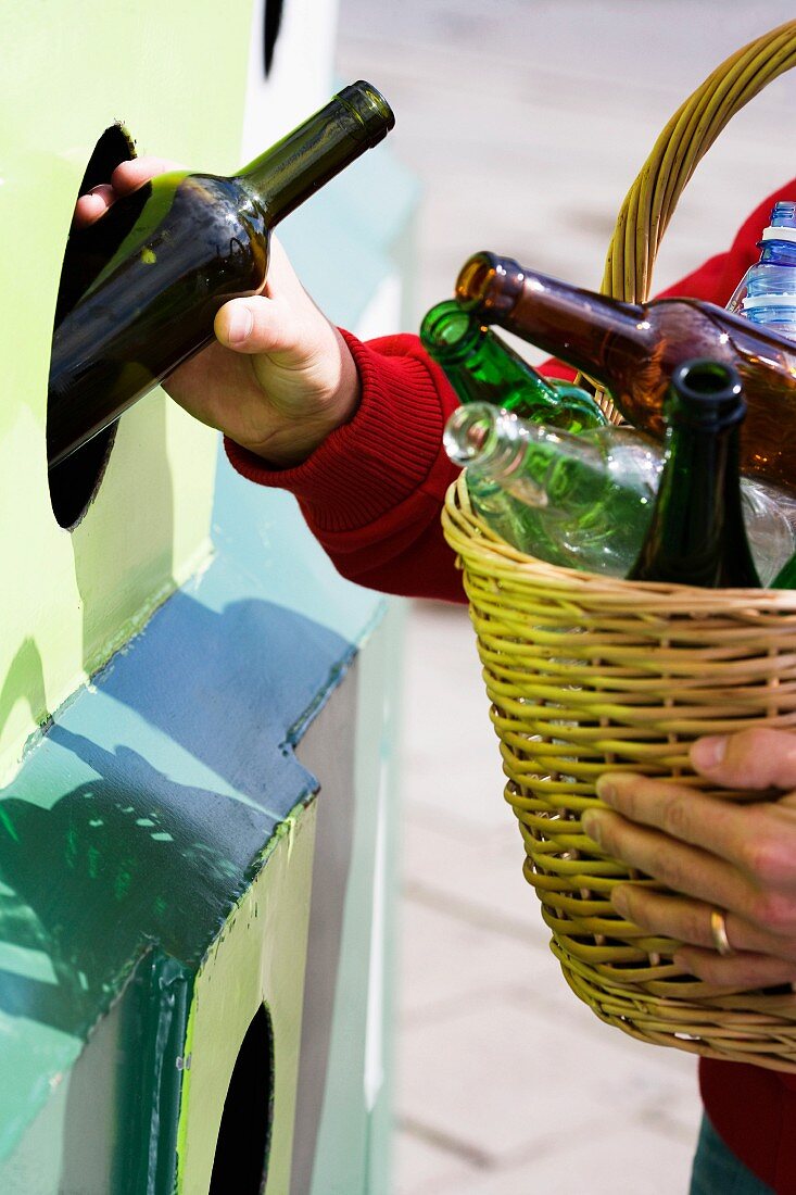 Person mit Flaschen beim Glasrecycling