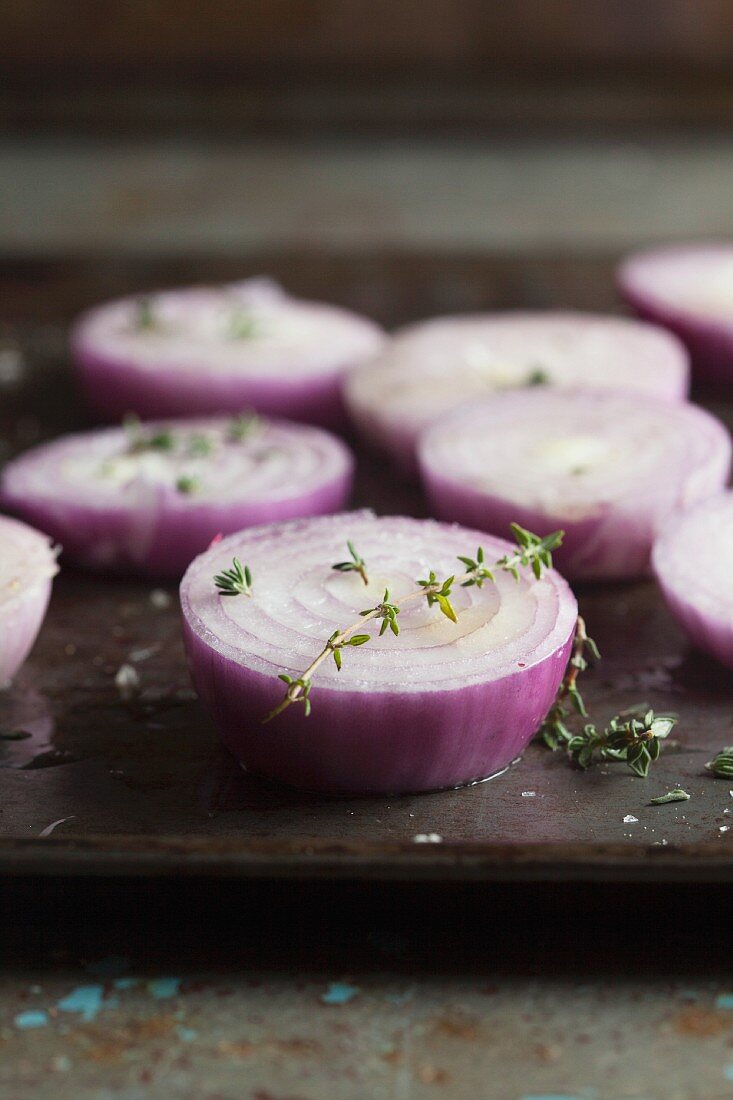 Red onions, in slices, for roasting on a baking tray (close-up)