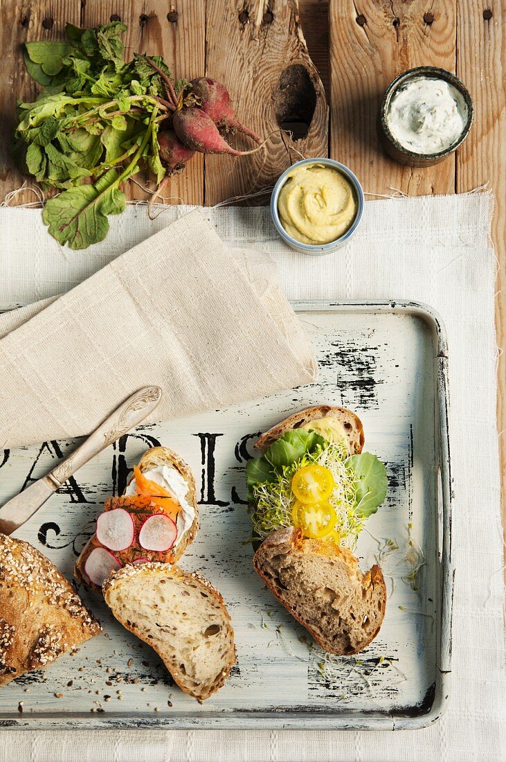 Gesunde Sandwiches (eins mit Räucherlachs und Radieschen, das andere mit Spinat, Sprossen und Kirschtomaten)