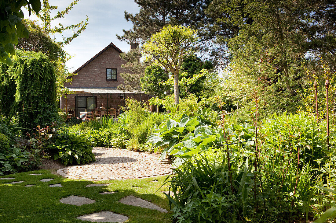 Circular terrace in summery garden with house in background