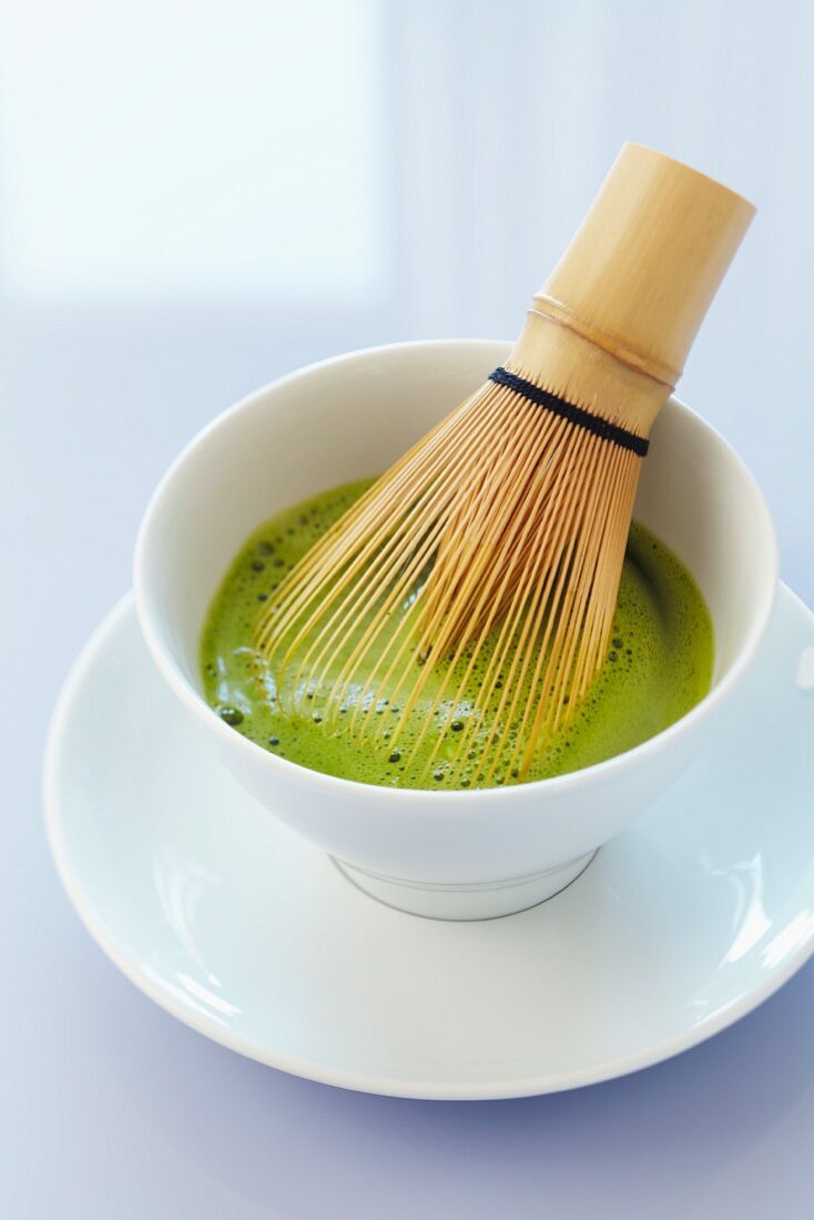 Matcha-Tee in Schale mit Bambusbesen
