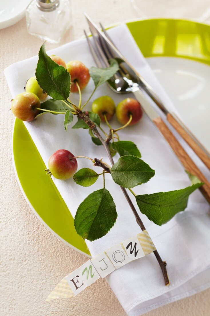 Table decoration: a sprig of ornamental apples on a plate with a label saying 'Enjoy'