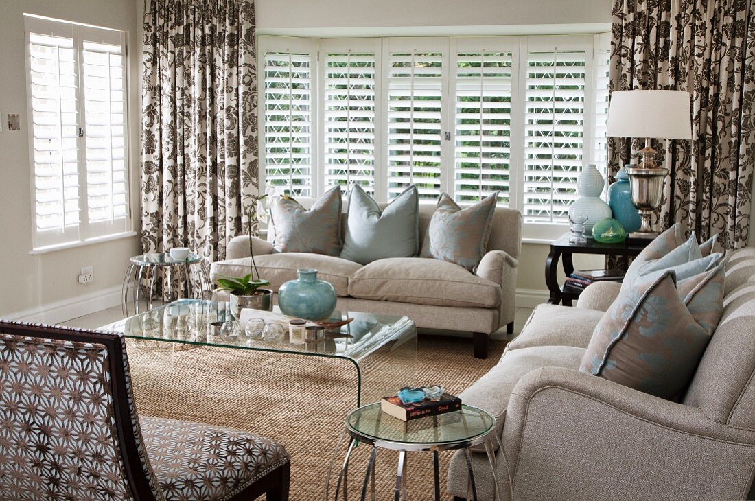 Living room with bay window, beige sofa set, plexiglass table and sisal rug