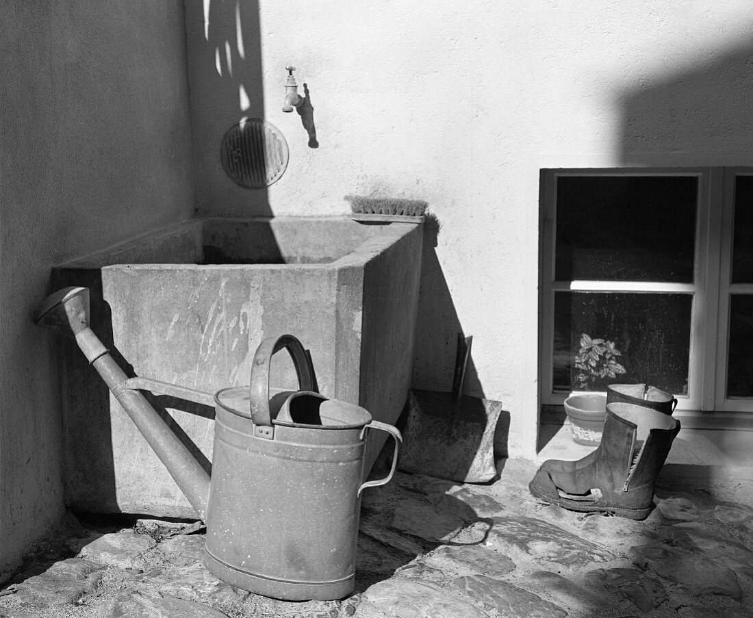 Watering can and wellington boots by water container (B&W)