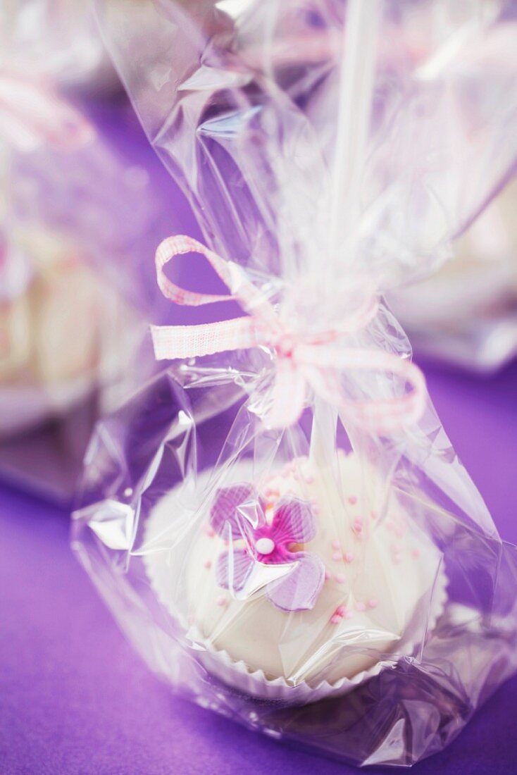 Cake pops on a purple surface, wrapped as a gift