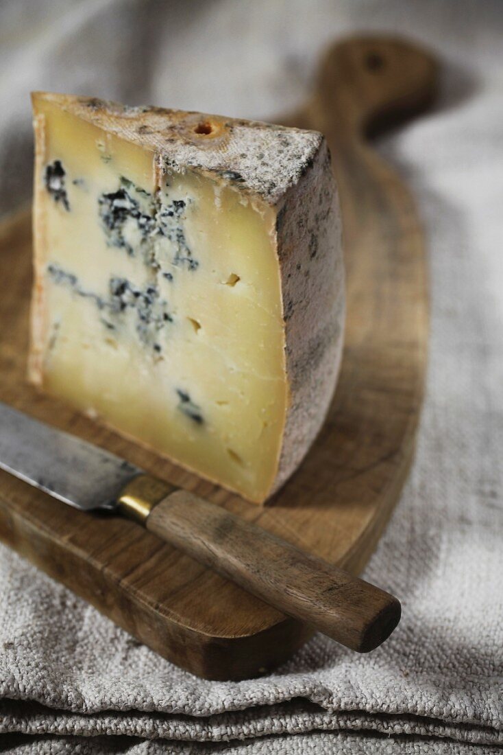 Gorgonzola with a knife on a wooden board