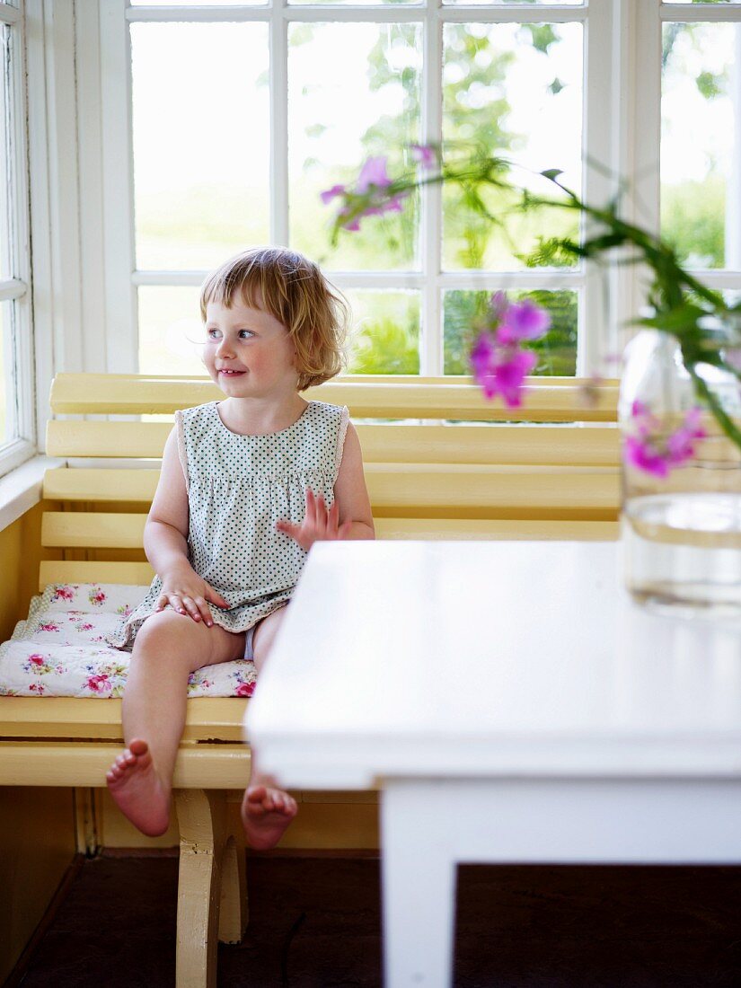 Little girl sitting on bench on veranda