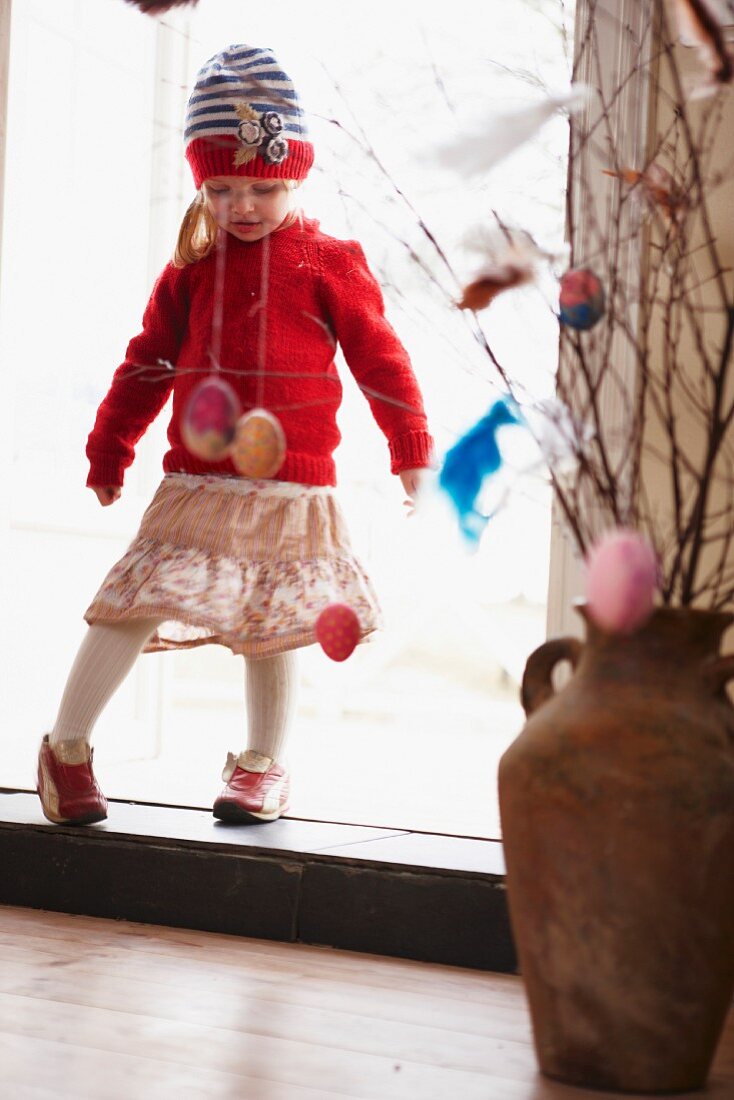 Little girl standing in doorway to room decorated for Easter