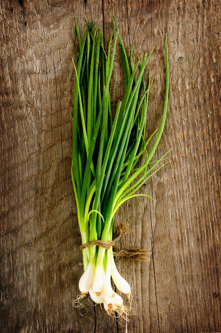 A bunch of spring onions on a wooden surface