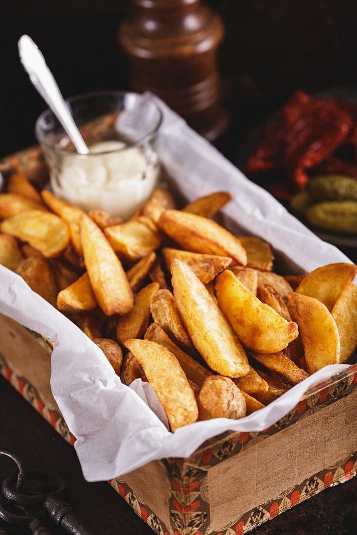 Fried potato wedges with white sauce in vintage box