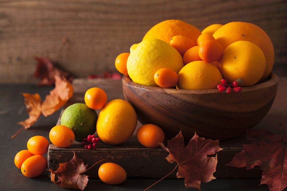 A still life featuring citrus fruits and autumn leaves