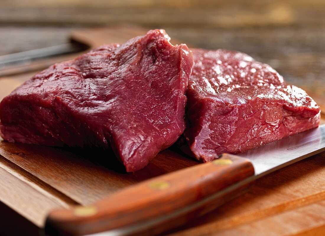 Venison steak raw on a chopping board