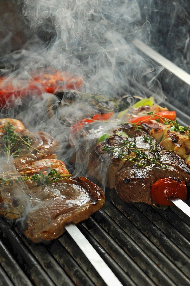 Beef steaks being barbecued on skewers