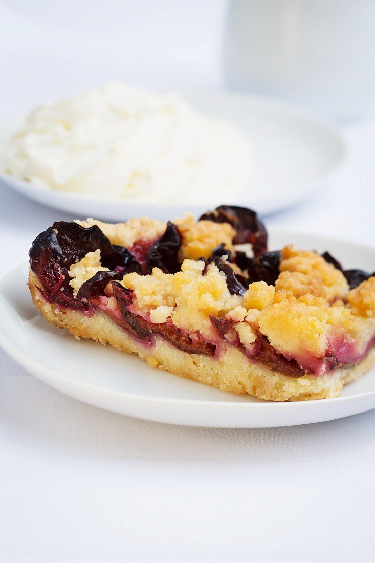 Ein Stück Pflaumen-Streusel-Kuchen mit Sahne