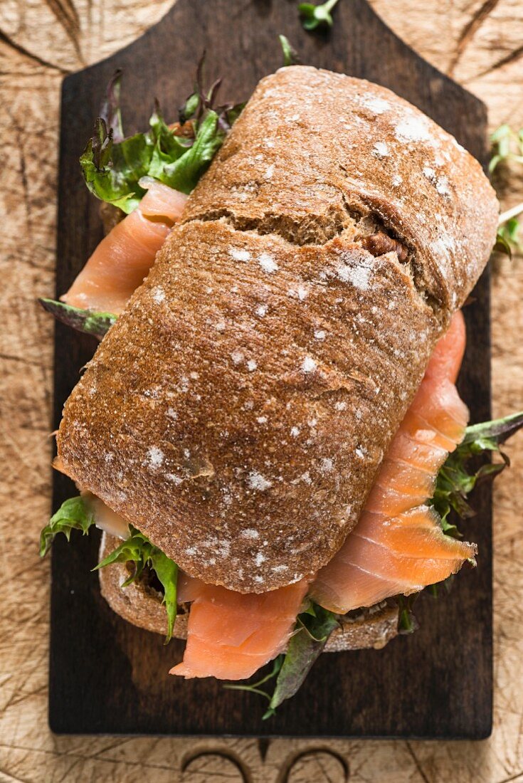 A smoked salmon and lettuce sandwich on a chopping board