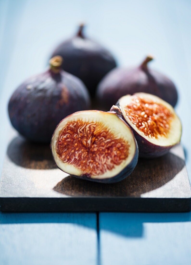 Fresh red figs on a chopping board, one cut in half