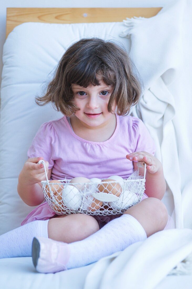 Little girl with wire basket of eggs