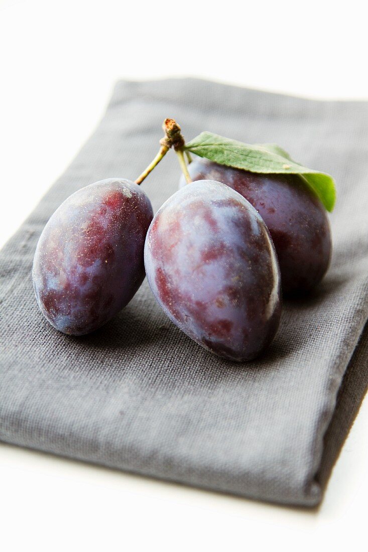 A bunch of three plums on a napkin