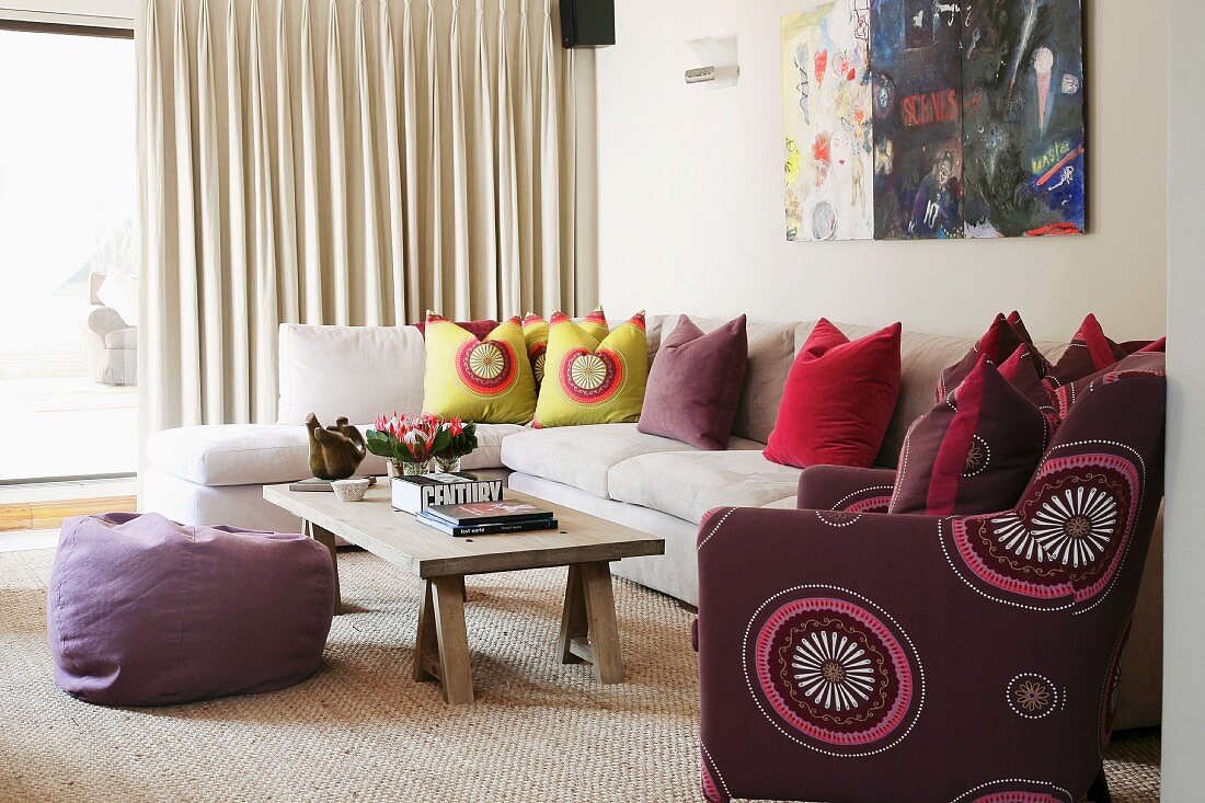 White chaise sofa with colourful scatter cushions, simple coffee table and purple beanbag on natural fibre rug