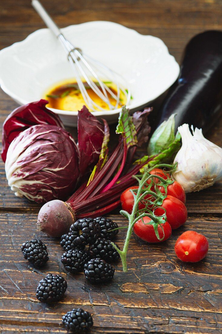 Verschiedene Gemüsesorten, Brombeeren und Vinaigrette auf Holztisch