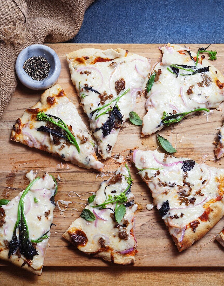 Pizza mit Stängelkohl, Spinat & Basilikum auf Holzbrett